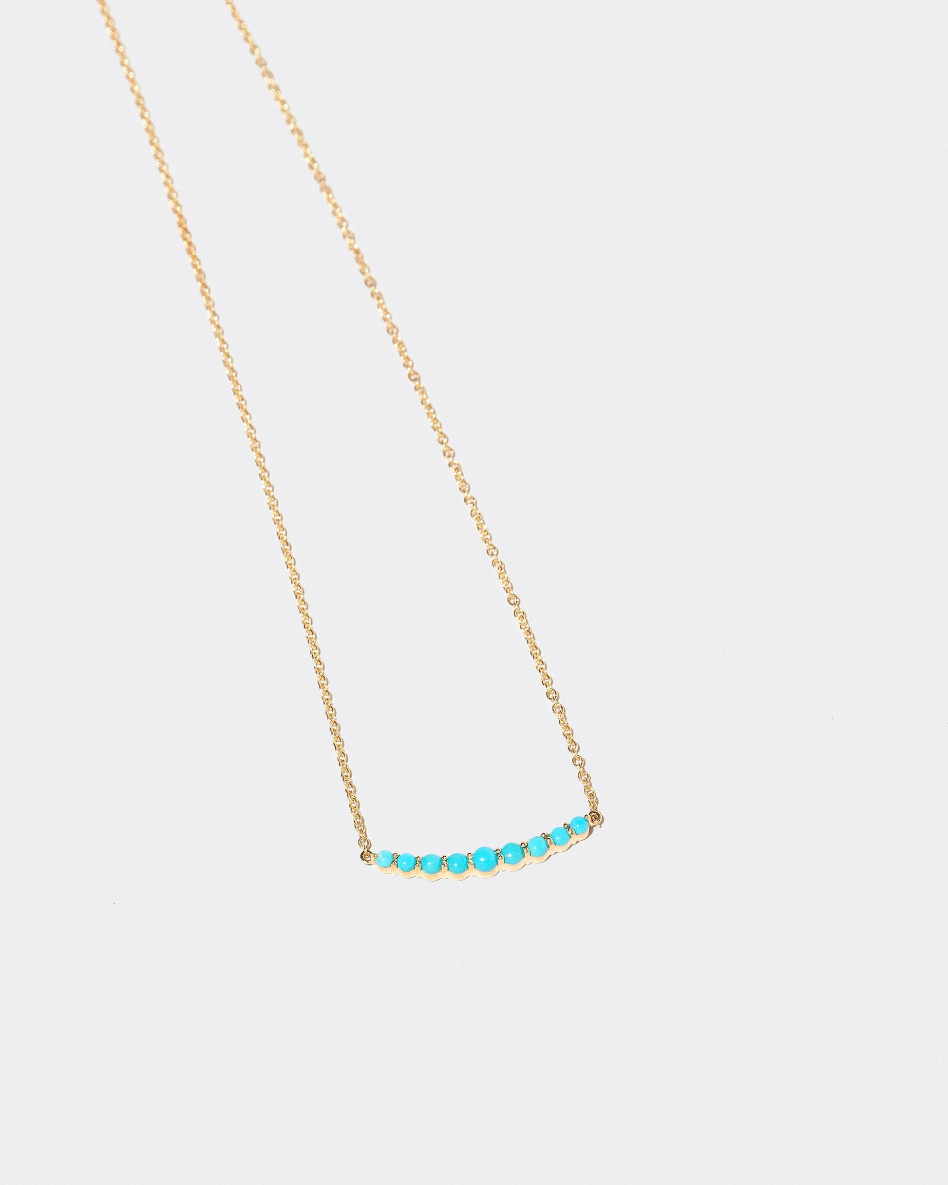 Closeup detail of the Turquoise Crescent Necklace on light color background.