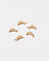 Group of Croissant Charms on light color background.