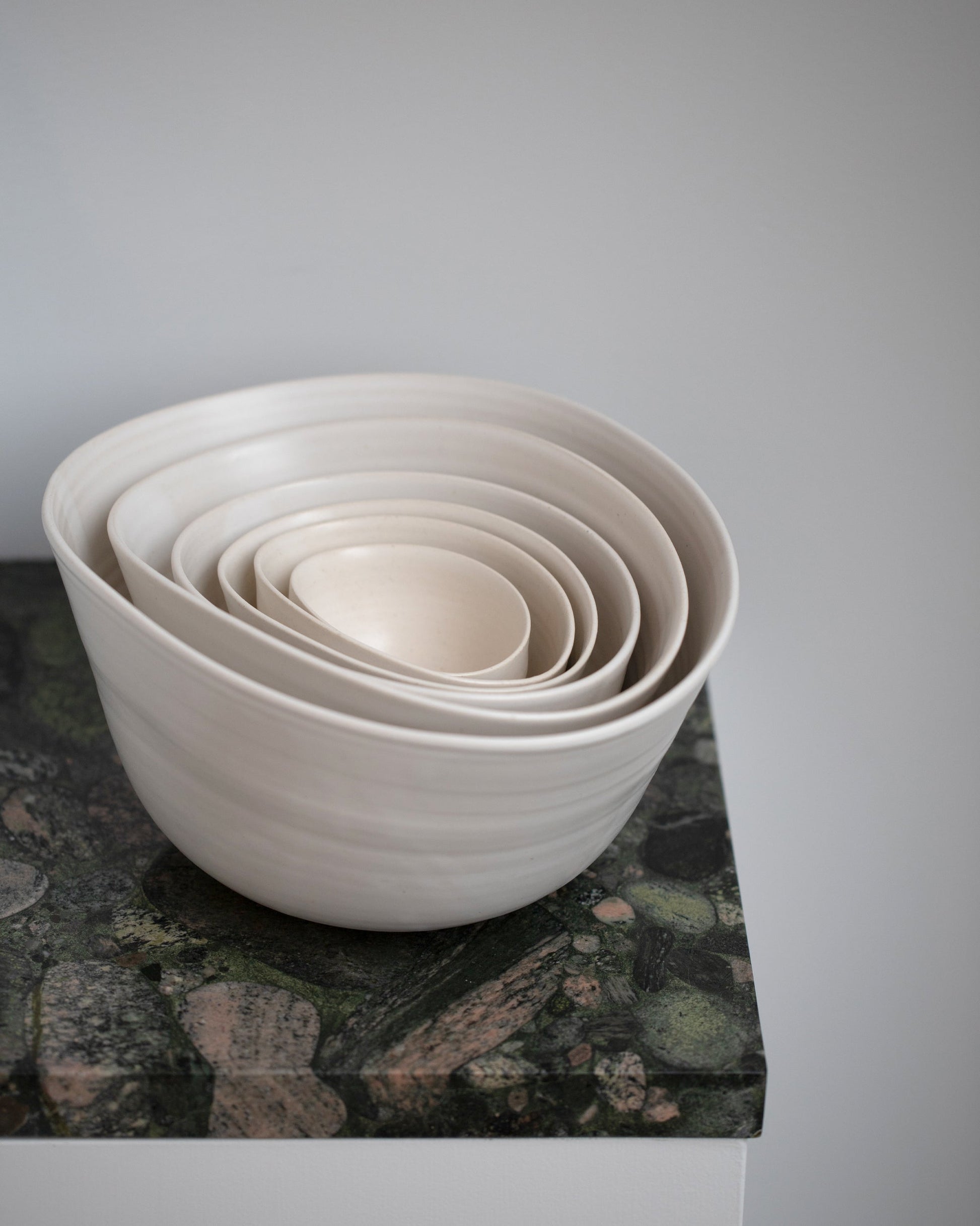 Styled image of a group of Eric Bonnin Off-White Sylvia Bowl #3, Sylvia Bowl #1/4, Sylvia Bowl #4, Sylvia Bowl #1/2, Sylvia Bowl #2 and Sylvia Bowl #1 on light color background.
