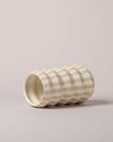 View from the side of the Jeremy Ayers White Striped Accordion Vase on light color background.