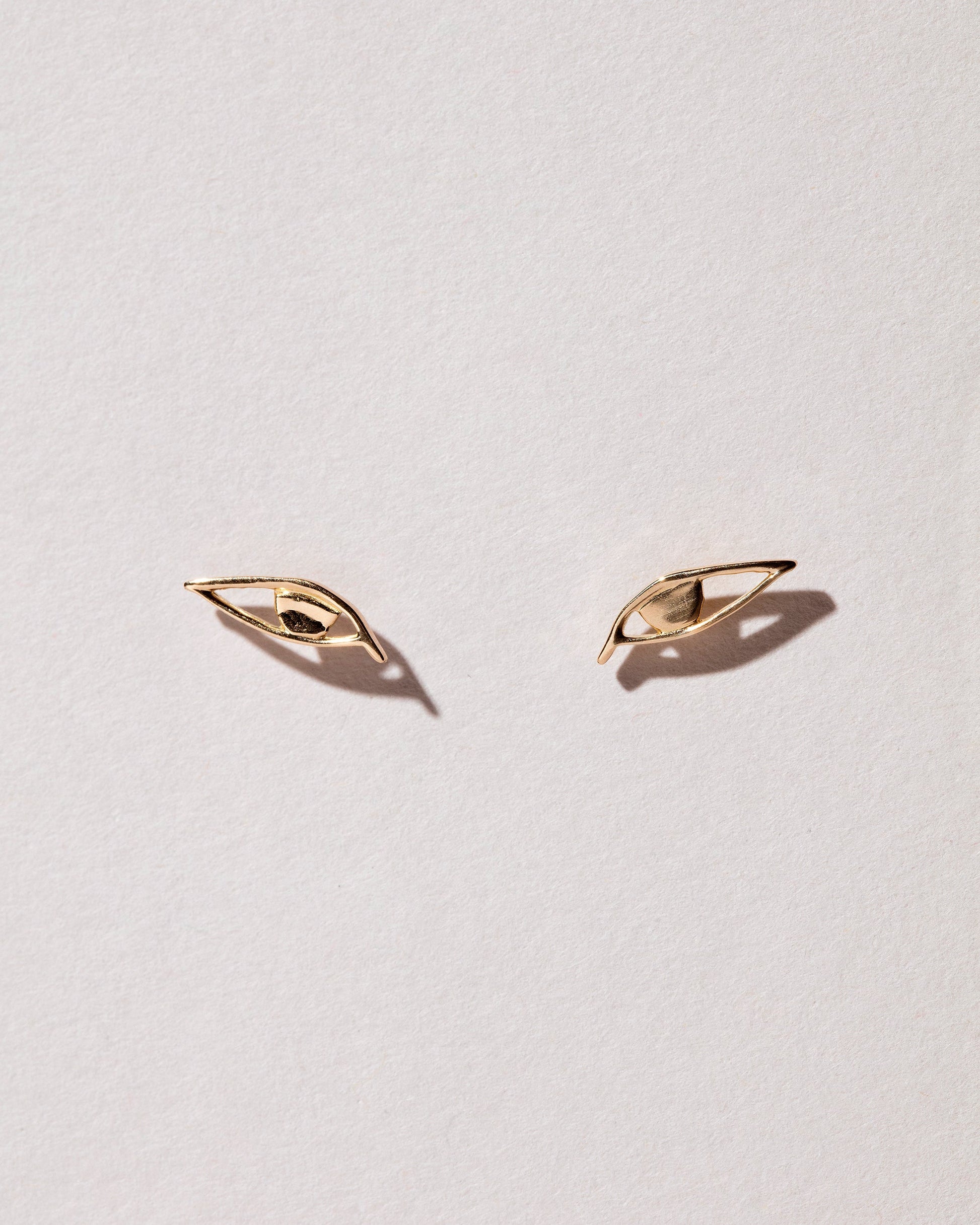 Left and Right Eye Stud Earrings on light color background.