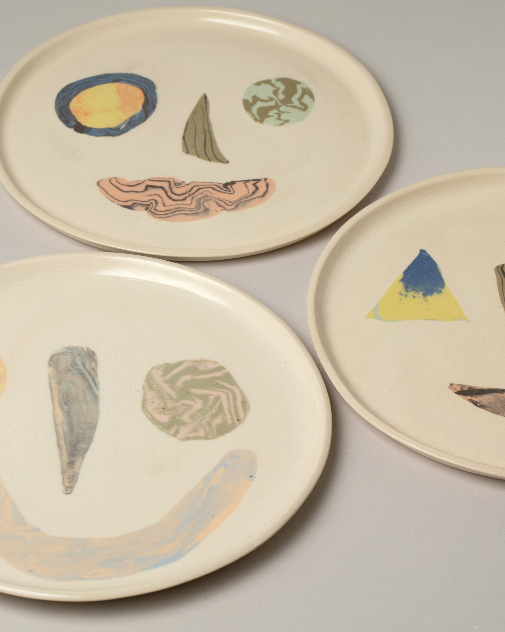Closeup details of a group of E.E. Ceramics Serving Plate - Smileys on light color background.