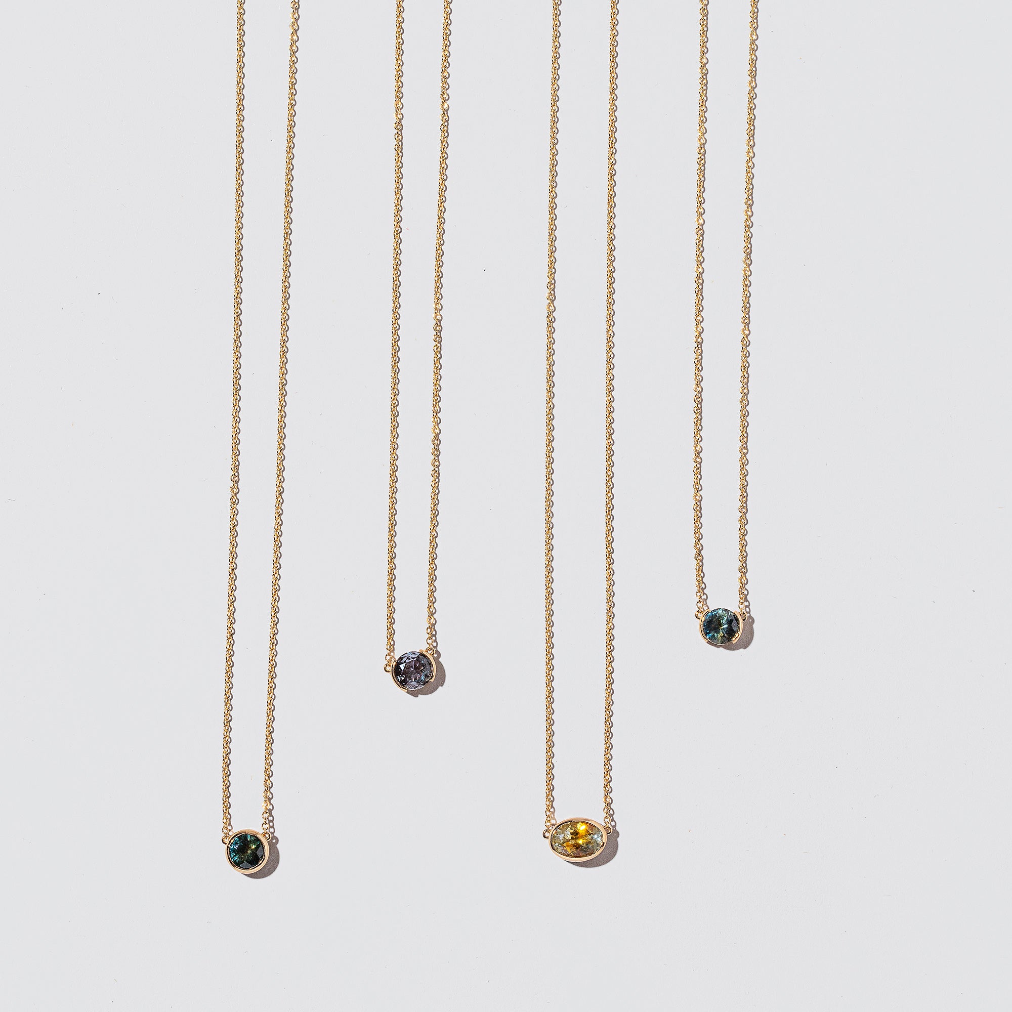 product_details::Group of Sapphire Cluster Necklaces on light color background.