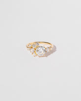 Cluster style ring with white diamonds set in 18k yellow gold, close up on light color background.