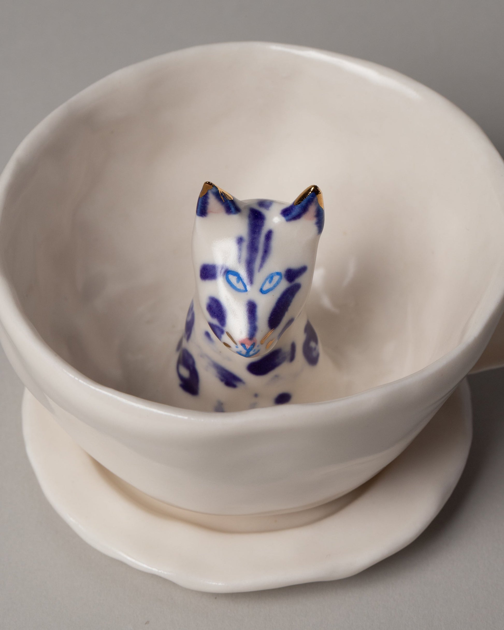Closeup detail of the Eleonor Boström Blue Spots Cat Tea Cup with Saucer on light color background.