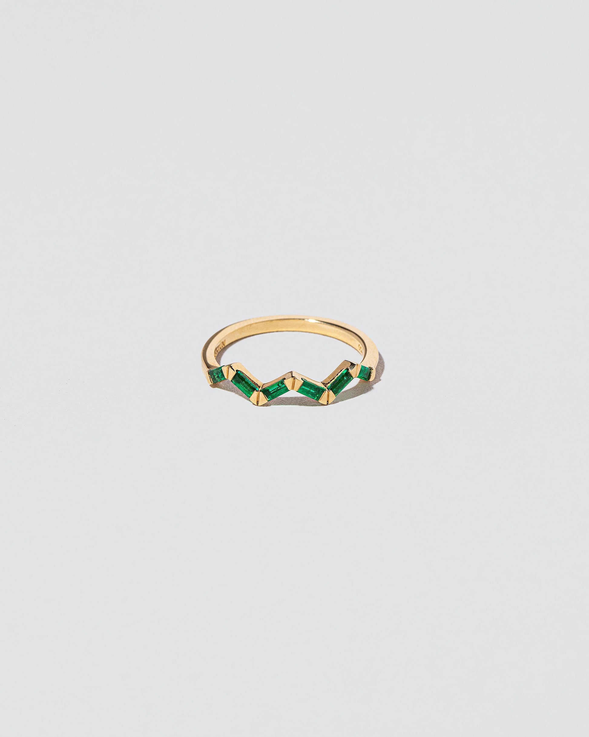 Emerald Baguette Yellow Gold Zig Zag Band on light color background.