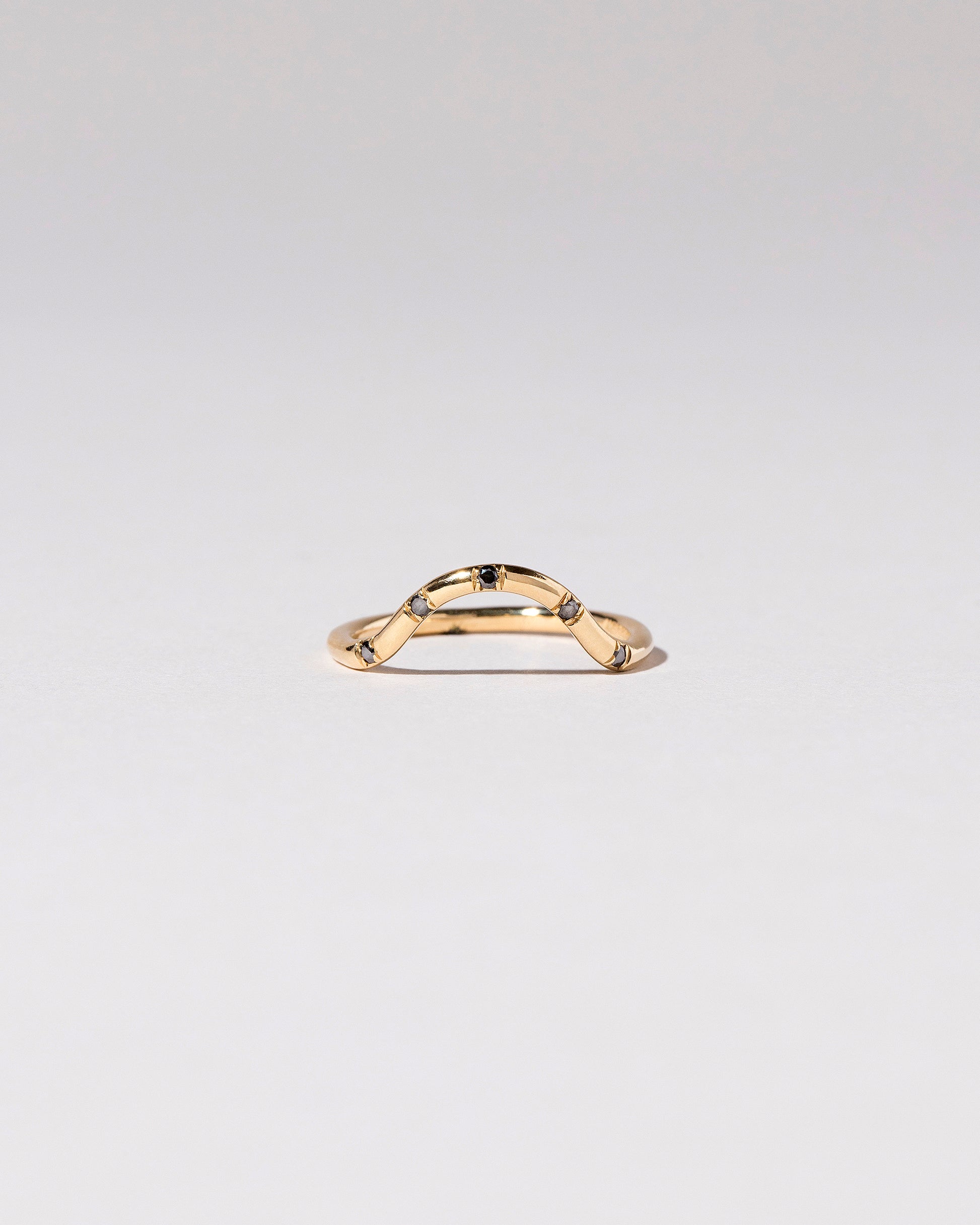 Gold Black Diamond Five Stone Curve Band on light color background.
