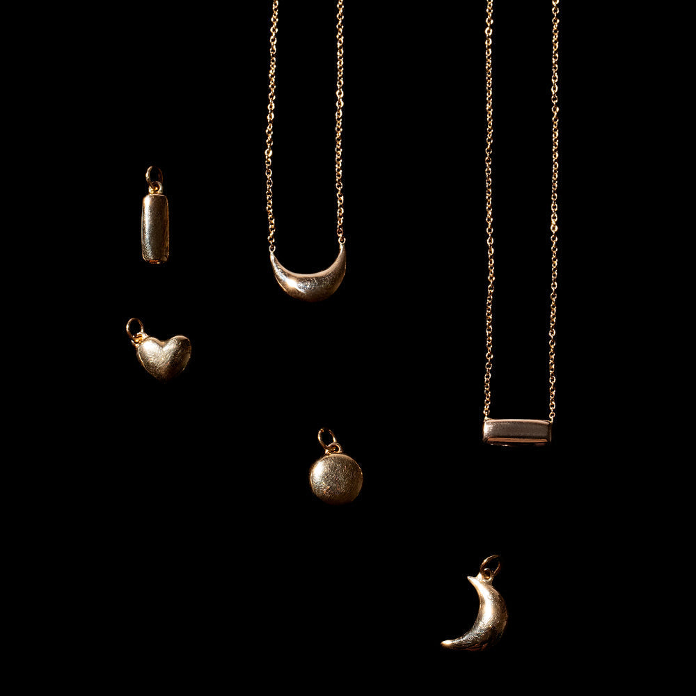 product_details::Time Capsule Necklaces and charms on black background.