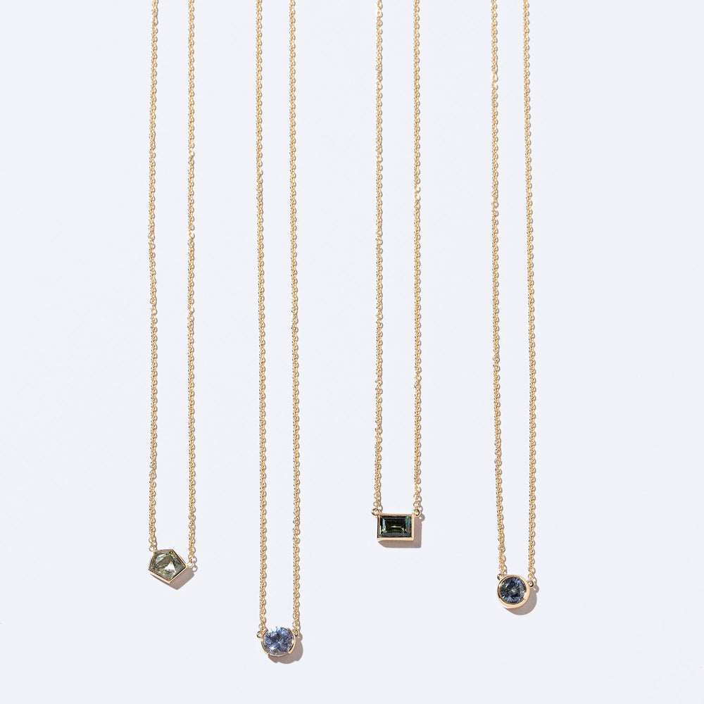 product_details::Geometric Sapphire necklaces on light colored background.