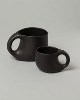Group of Dust and Form Large Charcoal and Small Charcoal Comfort Mugs on light color background.