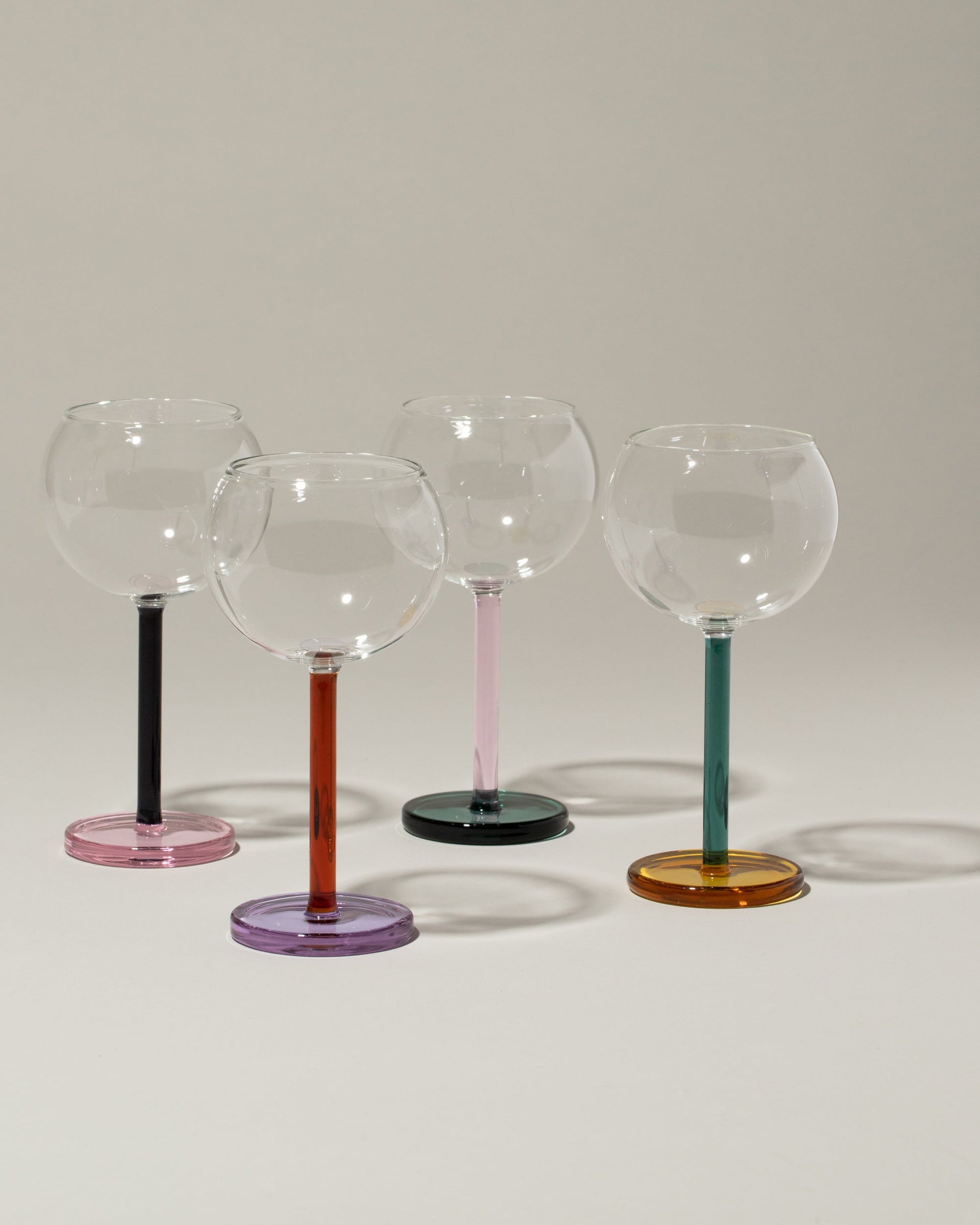 Group of Sophie Lou Jacobsen Evergreen & Honey, Pink & Evergreen, Midnight Blue & Pink and Amber & Lilac Bilboquet Wine Glasses on light color background.