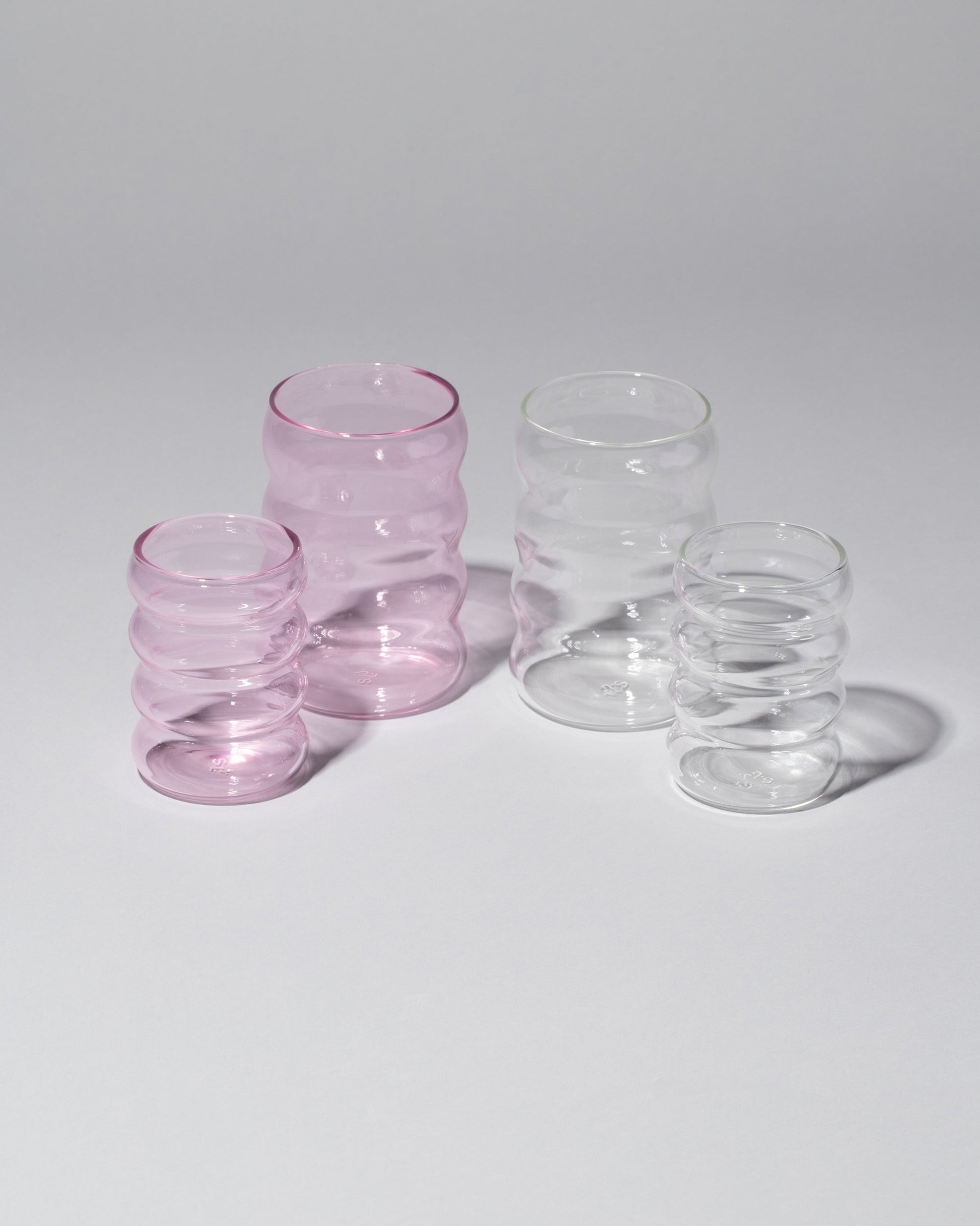 Group of Sophie Lou Jacobsen Small Pink, Large Clear, Small Clear and Large Pink Single Ripple Cups on light color background.