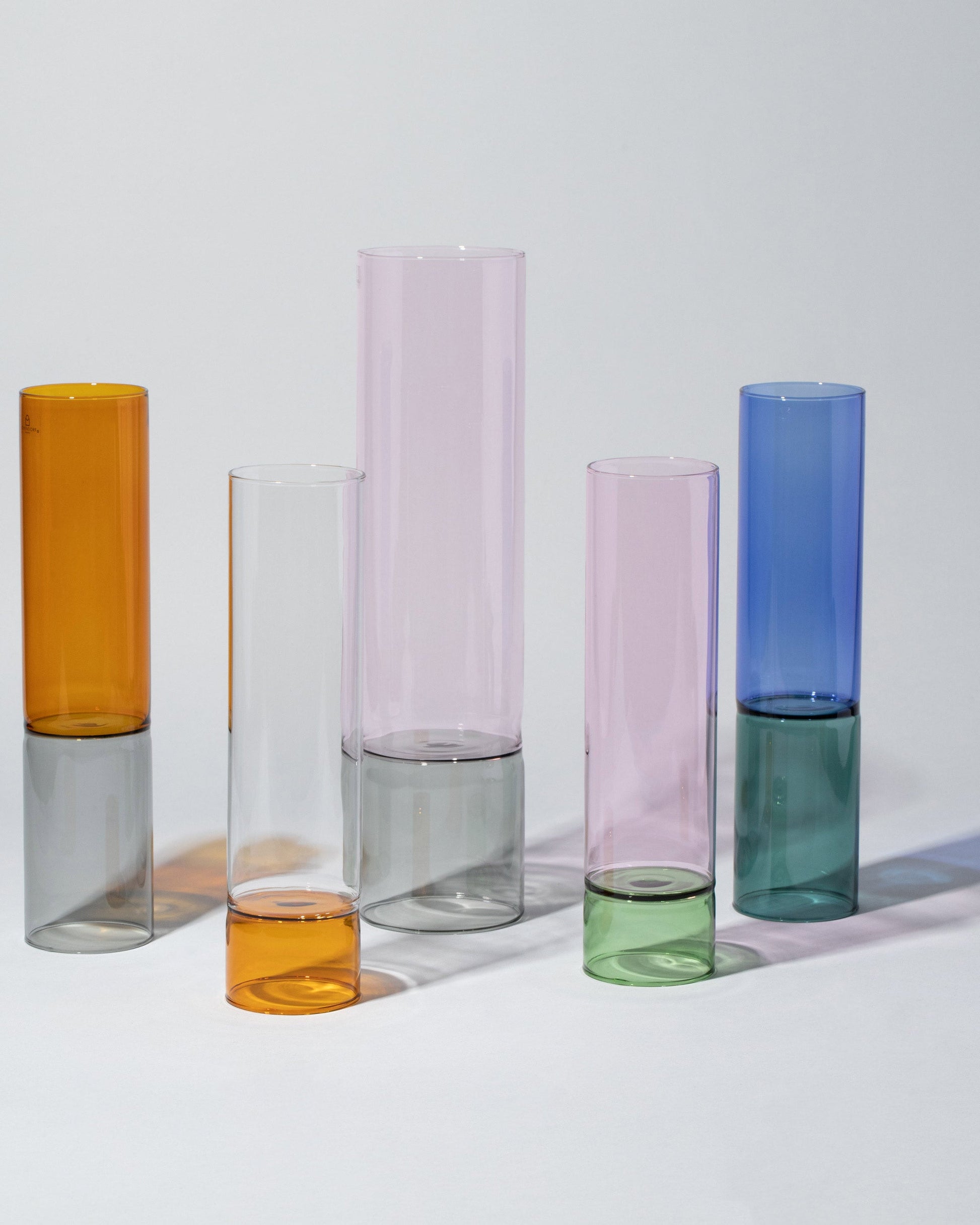 Group of Ichendorf Milano Medium Amber/Smoke, Small Pink/Green, Large Pink/Smoke, Small Clear/Amber and Medium Blue/Green Bamboo Vases on light color background.
