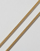 Closeup details of a group of 2mm Ritual Chain Necklaces on light color background.