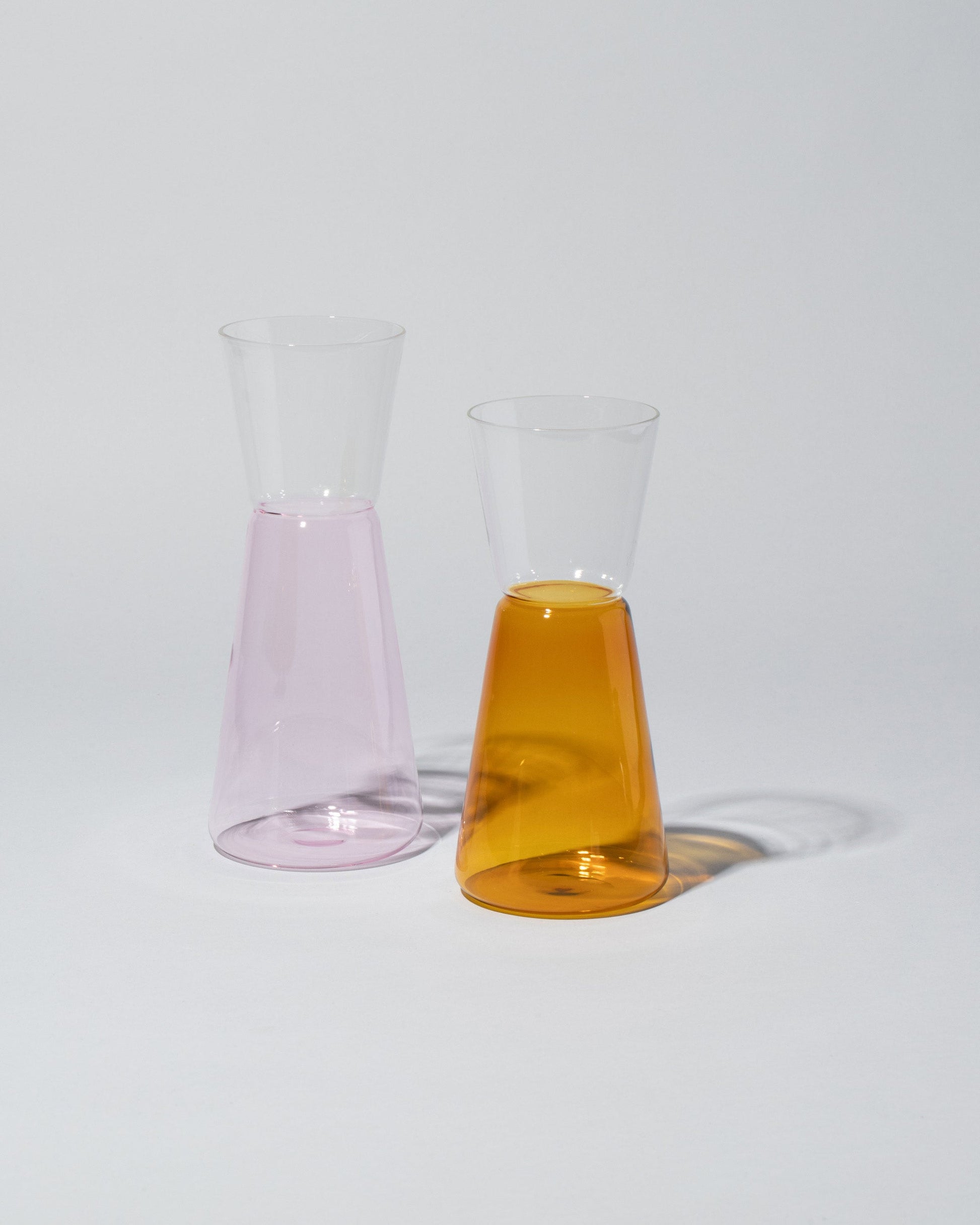 Group of Ichendorf Milano Large Pink & Clear and Small Amber & Clear High Rise Pitchers on light color background.