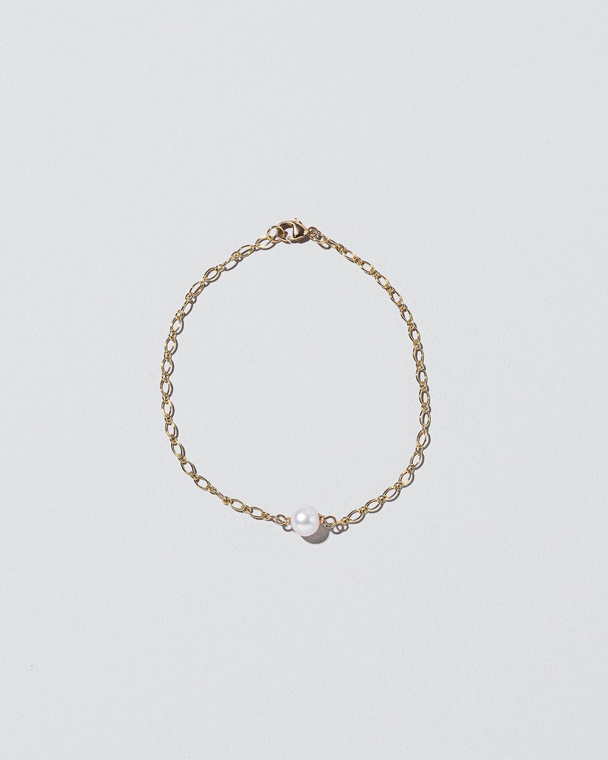 One Pearl Station Bracelet Open Oval Chain on light color background.