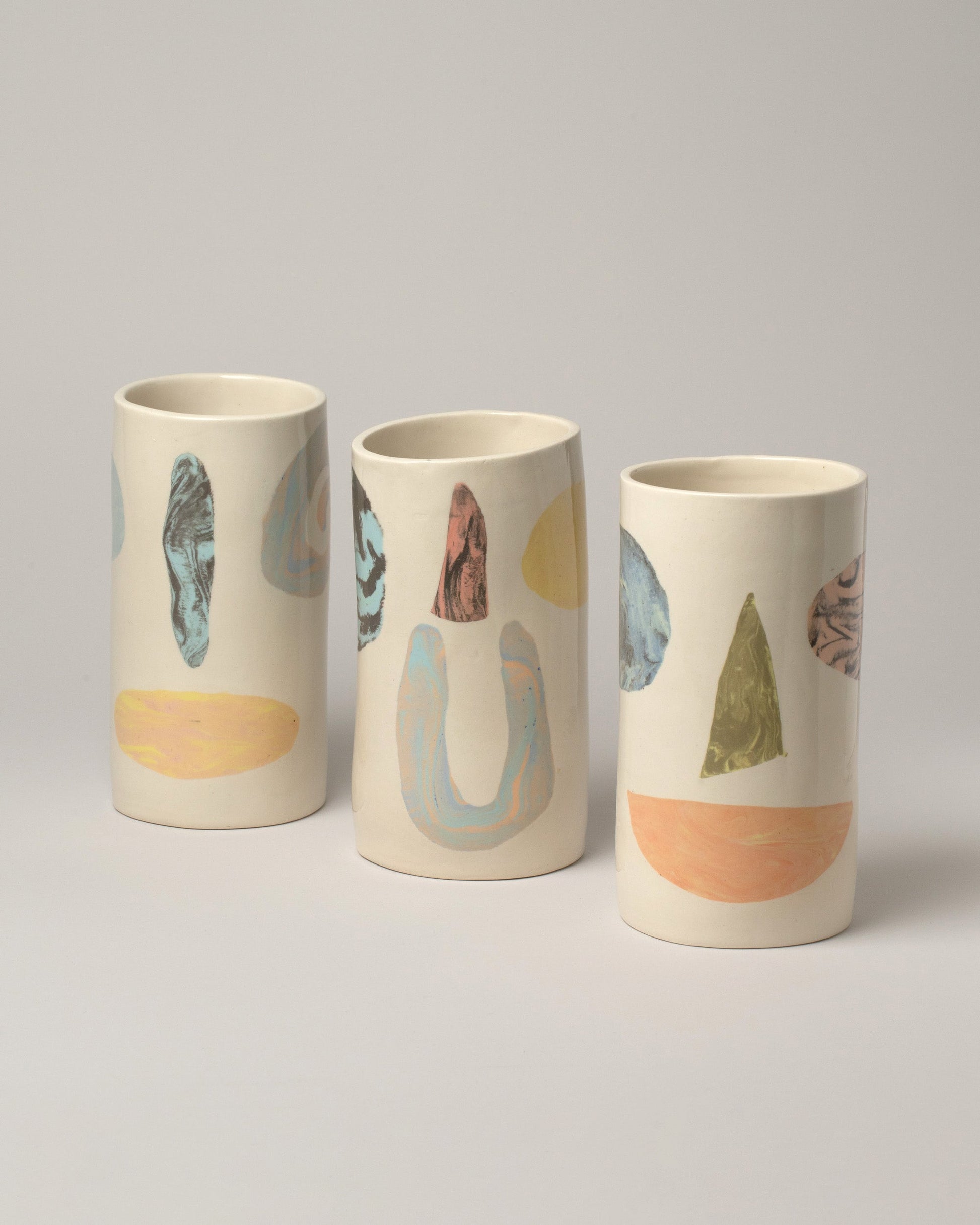 Group of E.E. Ceramics Smiley Vases on light color background.
