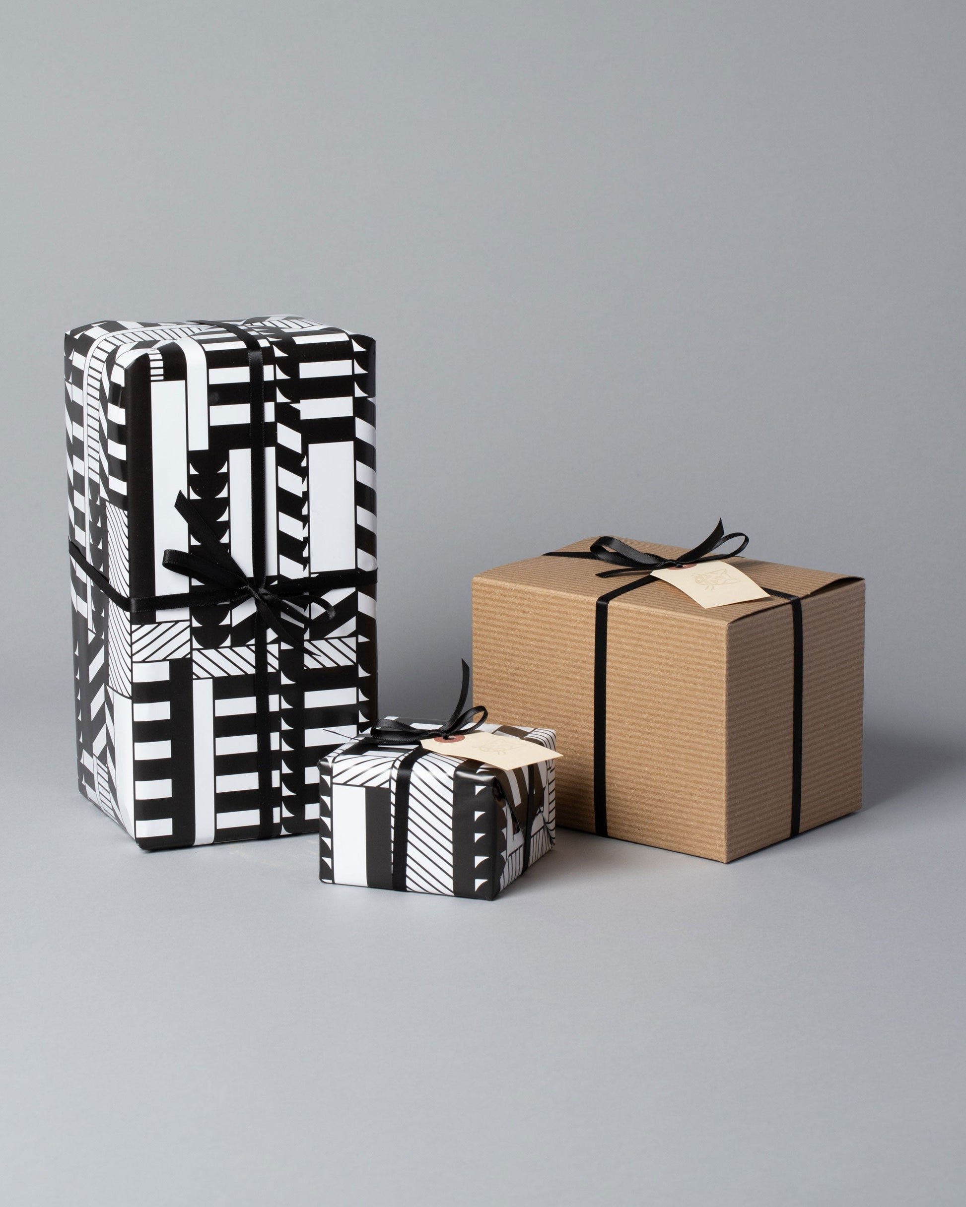 Gift Wrapping options, of black and white printed wrapping paper and cardboard boxes all wrapped with ribbon