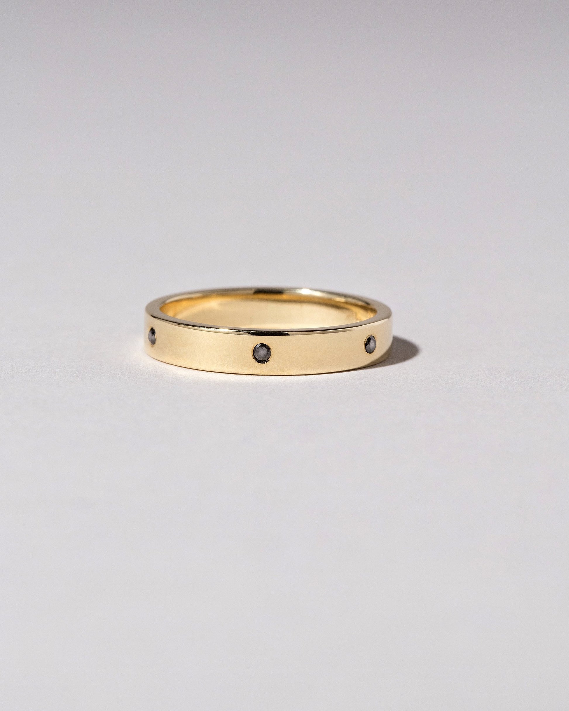Closeup detail of the Gold 4mm Square Wire Band with Six Stone Black Diamond 1.6mm added on light color background.