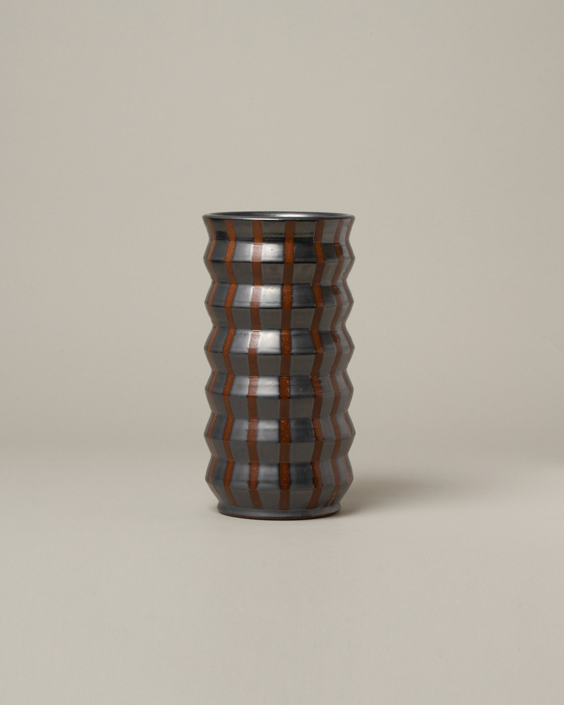 Jeremy Ayers Gunmetal Striped Accordion Vase on light color background.