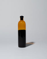 Ichendorf Milano Black/Amber Light Colore Bottle on light color background.