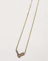 Closeup details of the Gold Baguette Bar Necklace on light color background.