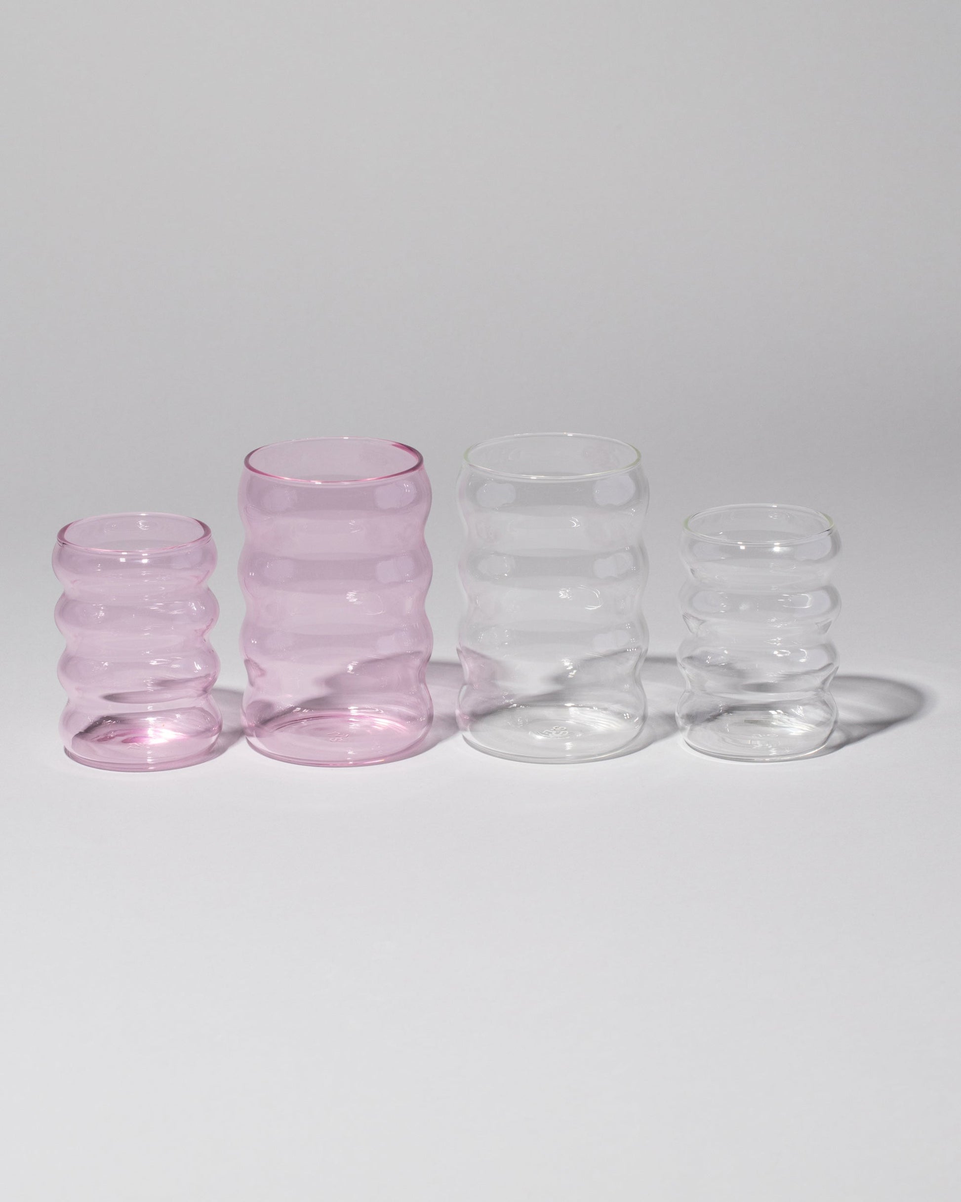 Group of Sophie Lou Jacobsen Small Pink, Large Clear, Small Clear and Large Pink Single Ripple Cups on light color background.