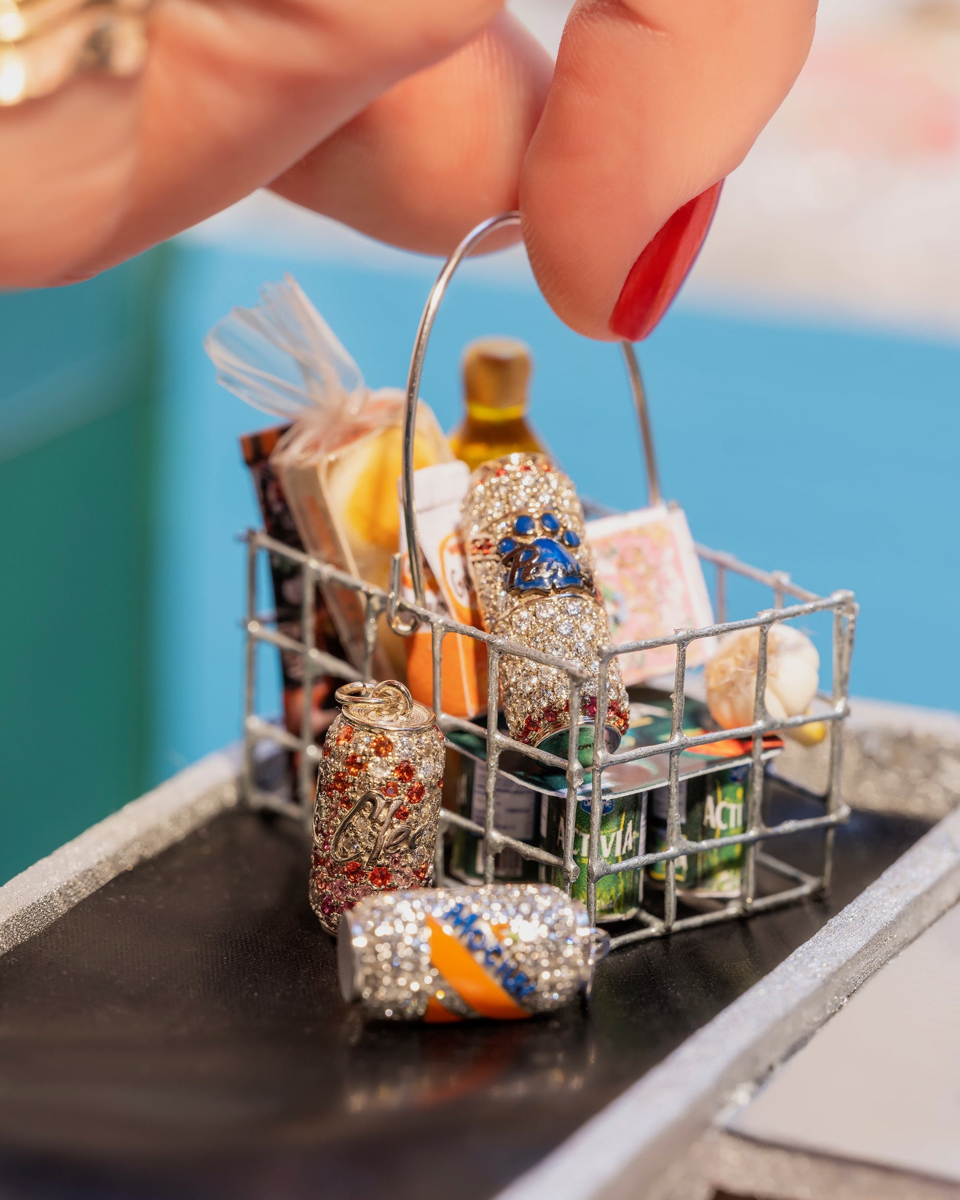 Color photo of hand holding miniature shopping basket with aluminum can charms