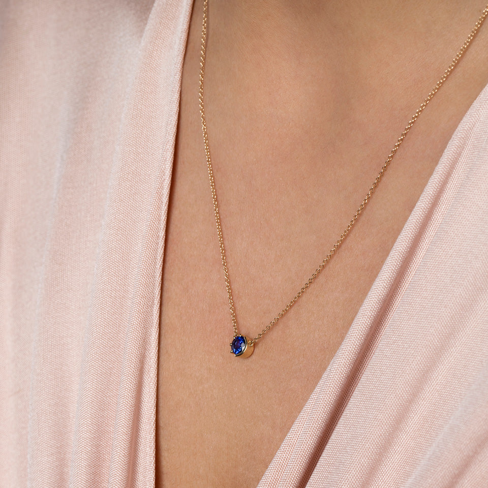 product_details::Closeup view of the Sapphire Sun & Moon Necklace on model.
