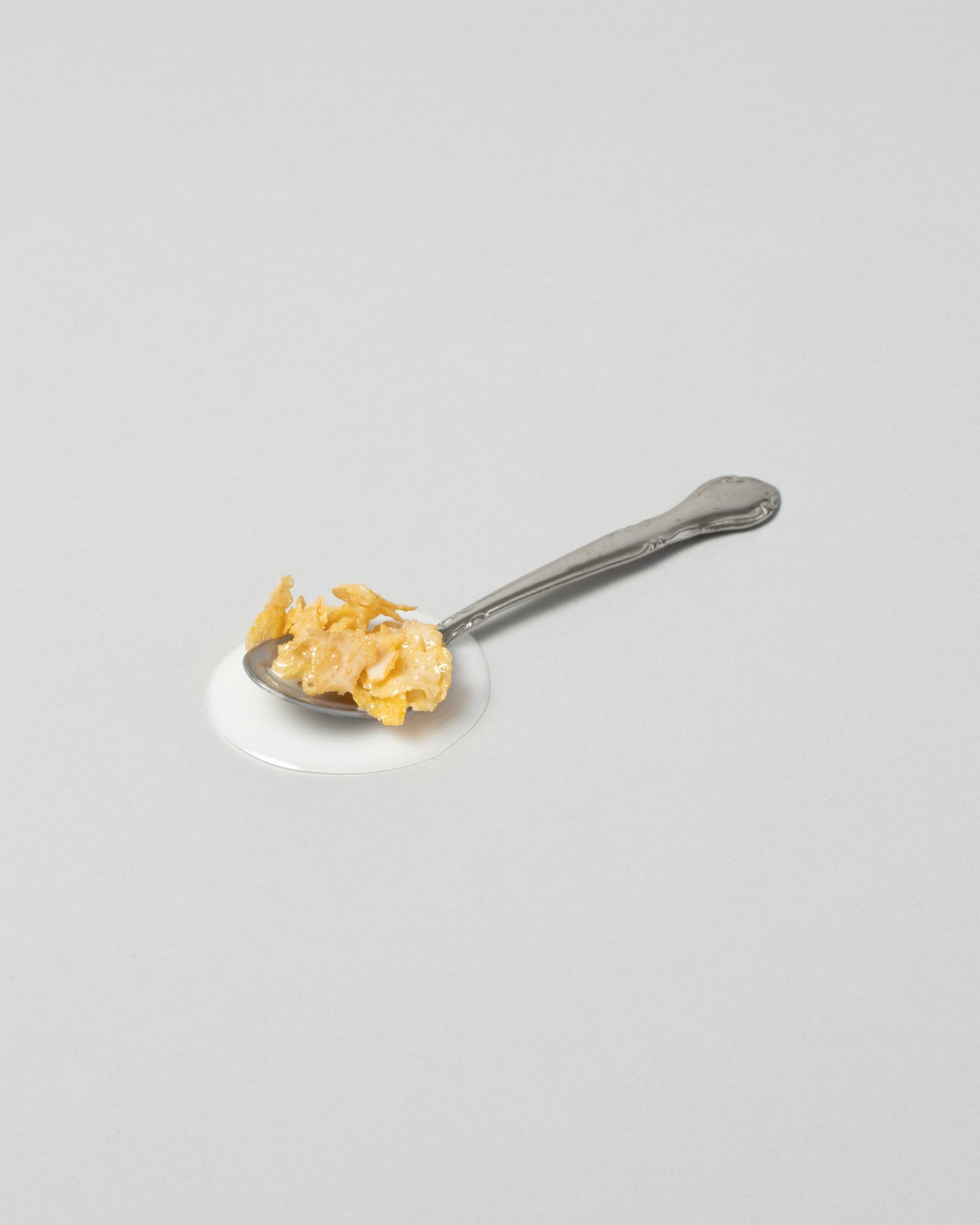 Spills Corn Flakes Spoon on light color background.