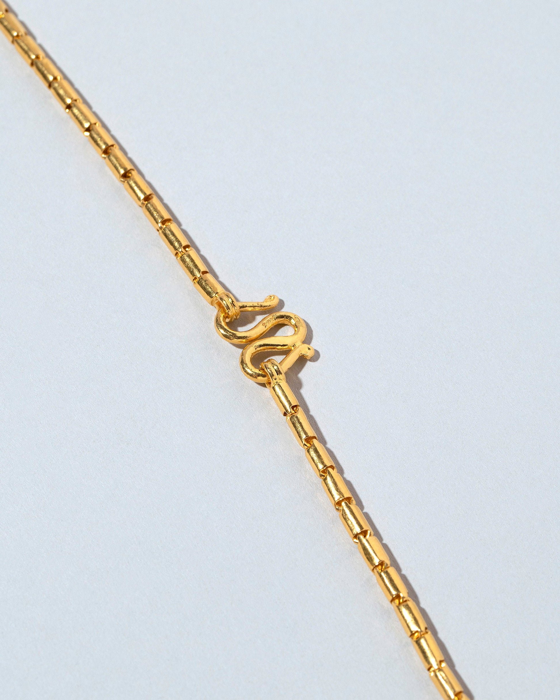 Closeup details of the Serpiente Chain Necklace on light color background.