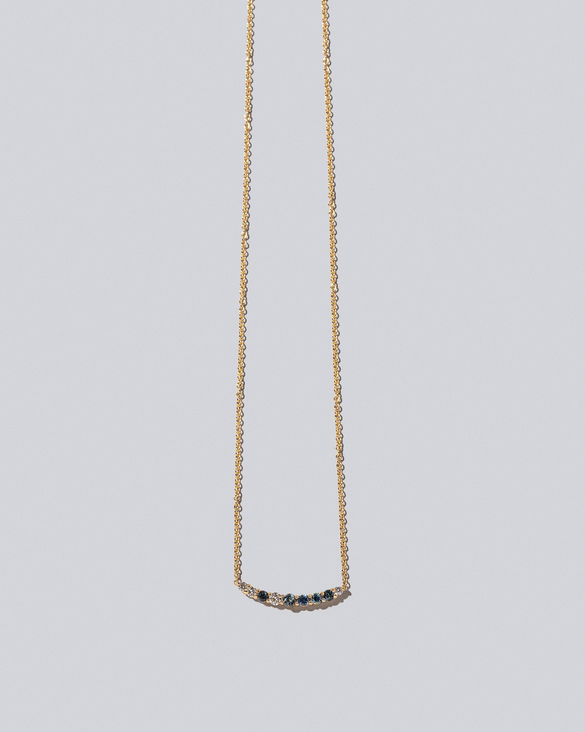 Sapphire & White Diamond Crescent Necklace on light color background.