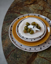 Styled image featuring Recreation Center Dot Dinner Plate, Dot Salad Plate, La Ceramica Vincenzo Del Monaco Carmel Yellow Shallow Bowl, and Eleonor Bostrom Dog Ring Dish. 