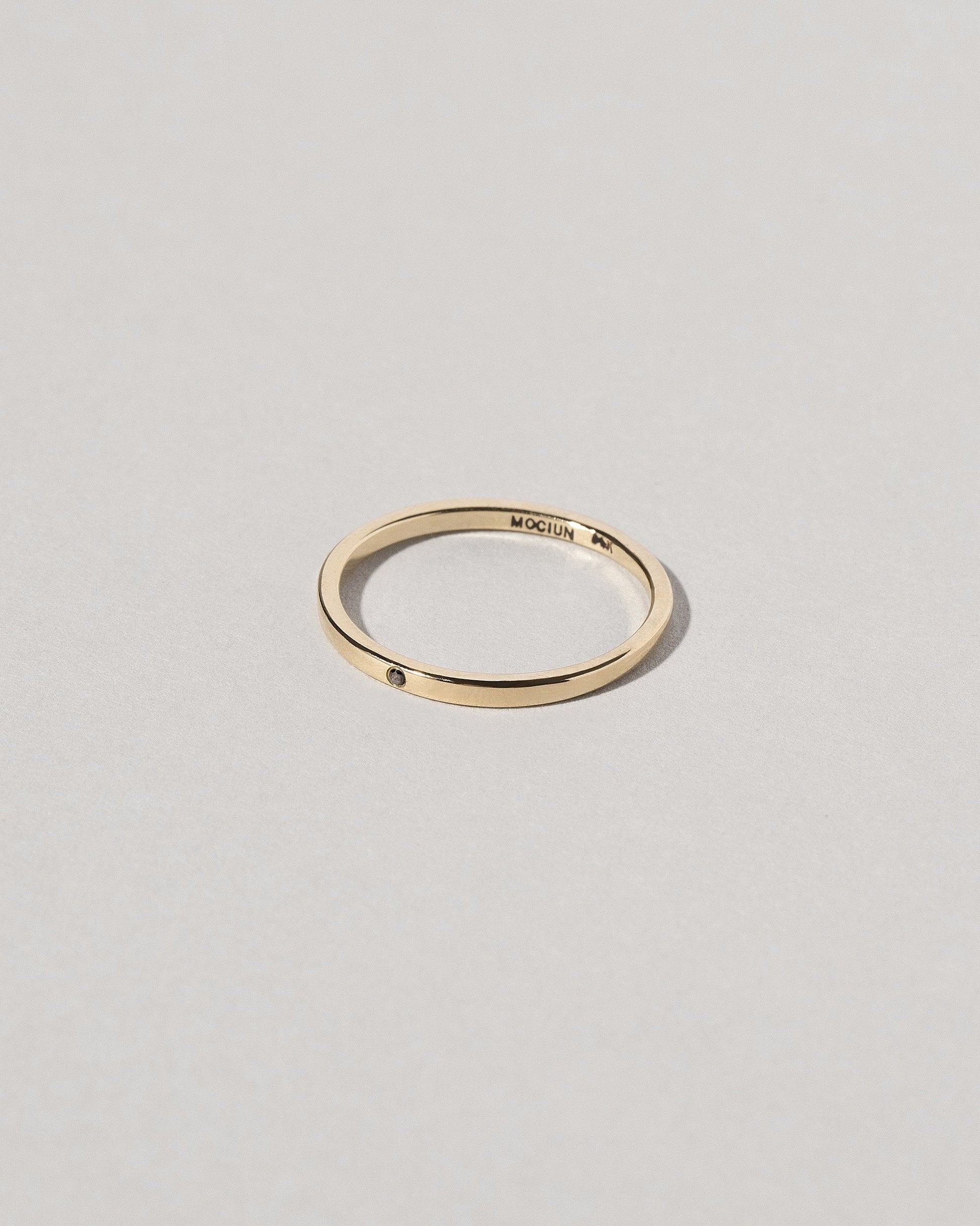 View from the side of the Gold 1.5mm Square Wire Band with Single Stone Black Diamond 1.3mm on light color background.