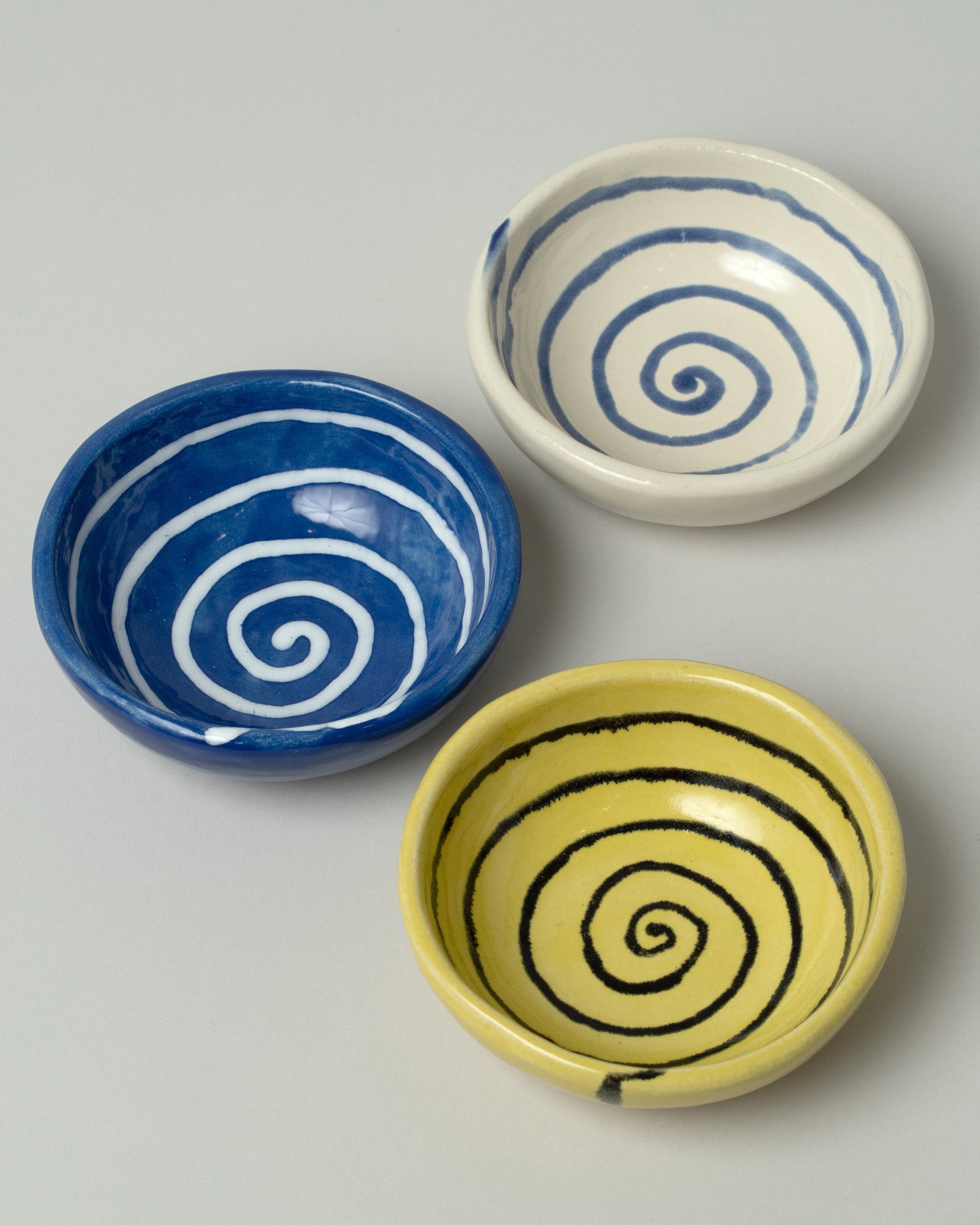 Closeup details of a group of Casa Veronica Leche, Sol and Azul Mini Vida Bowls on light color background.